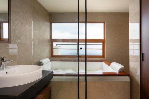 a bathroom with a tub and a sink and a window at Olive Woods in Chinnakanal