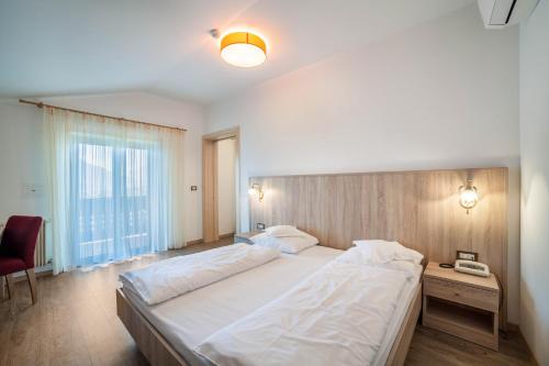 a bedroom with a large white bed and a chair at Gartenheim App Elisabeth in Schenna