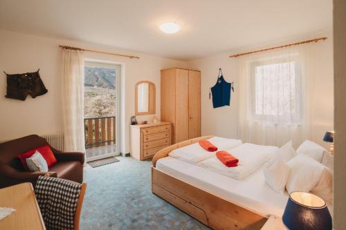 a bedroom with a bed and a chair and a window at Garni Unterweggütl in Naturno