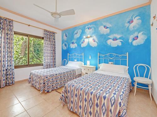 a bedroom with two beds and a blue wall at El Bosque in Llucmajor