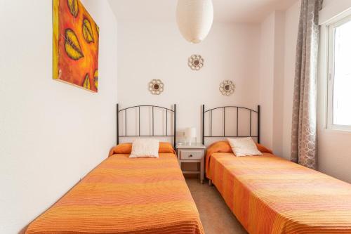 two beds in a small room with a window at Apartamento Turquesa Nerja in Nerja