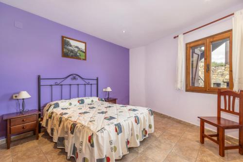 a bedroom with a bed with purple walls and a window at Xisqueta in Campo