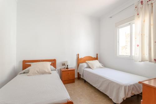two beds in a white room with a window at Planta uno Valle de Abdalajis in Valle de Abdalagís