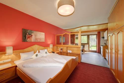a bedroom with a large bed with a red wall at Alpenhof Lodge Almrose iii in Saltusio