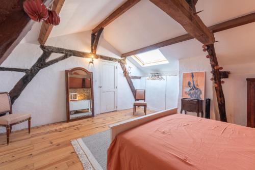 an attic bedroom with a bed and a chair at Maison Blousson, Longère gersoise in Malabat