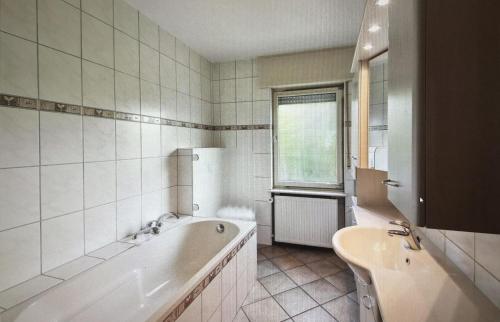 a white bathroom with a tub and a sink at Haus Milaneva in Klotten