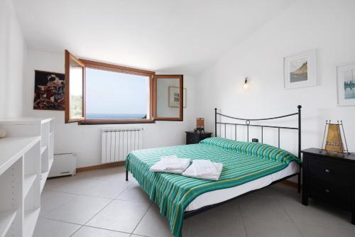 a bedroom with a bed with a green striped sheets at Villa Ciò in Bonassola