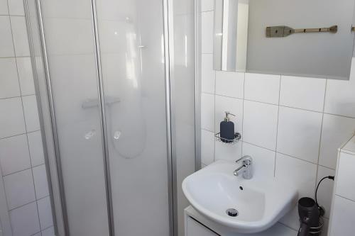 a white bathroom with a shower and a sink at Ferienhaus Eifelträume, Birresborn in Birresborn