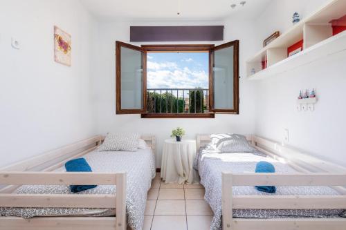 two beds in a room with a window at Casa Arturo in Sa Coma