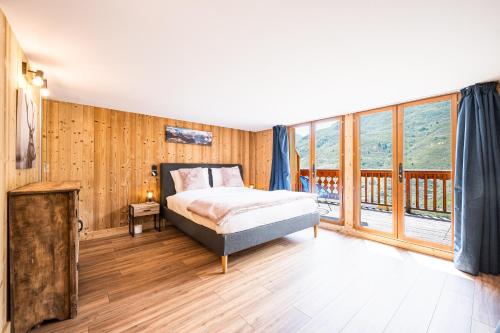 a bedroom with a bed and large windows at Chalet Delphine Luxe, Ski aux pieds in Les Bruyères