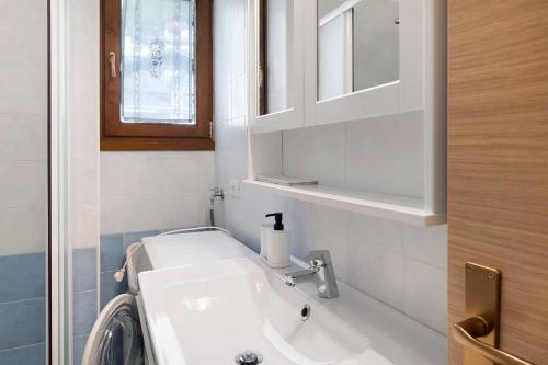 a white bathroom with a sink and a window at Super Mini Appartamento Lanzada in Lanzada