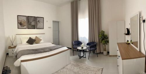 a white bedroom with a bed and a table and chairs at رخاء للغرف الفندقية in Firq