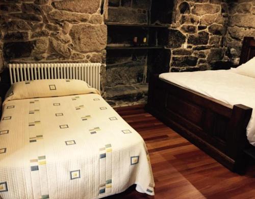 a bedroom with two beds and a stone wall at O Cantón in La Bola