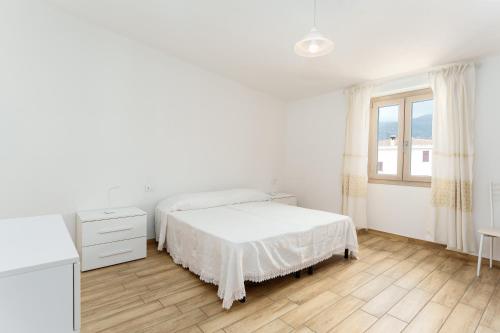 a white bedroom with a bed and a window at Enjoy The Silence Flat in Orosei