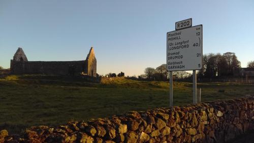 a sign next to a stone wall with a castle in the background at Garden View Self Catering Lough Rynn in Mohill