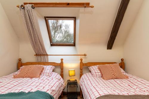 two beds in a room with a window at Les gîtes Bretons in Bieuzy-les Eaux