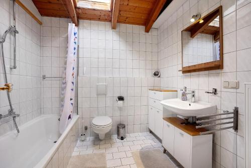 a bathroom with a sink and a tub and a toilet at Schnitzer Ferienwohnung in Görisried