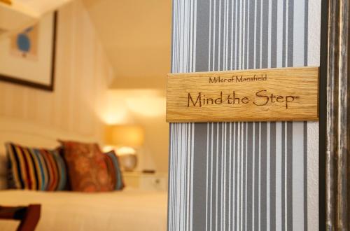 a wood sign that reads mind the step on a wall at The Miller of Mansfield in Goring