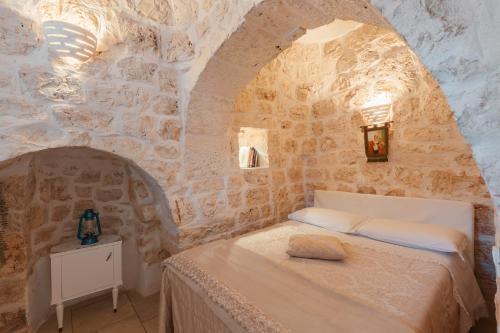 a bedroom with a bed in a stone wall at Trullo Milù in San Michele Salentino