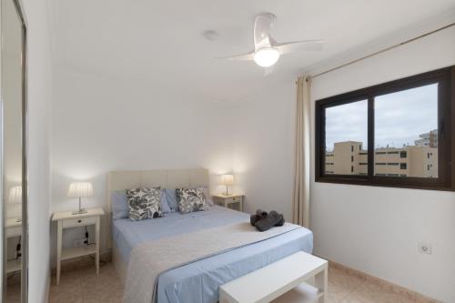 a white bedroom with a bed and a window at Lirio Blanco de las Dunas Canarias in Playa del Ingles