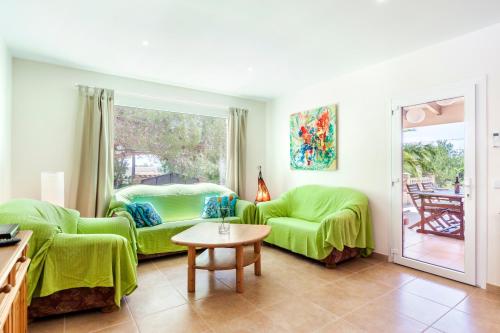 a living room with two green couches and a table at Casa Antonio Invierno in Cala Llombards
