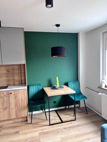 a dining room with a table and green walls at elli apartament Sieradz in Sieradz