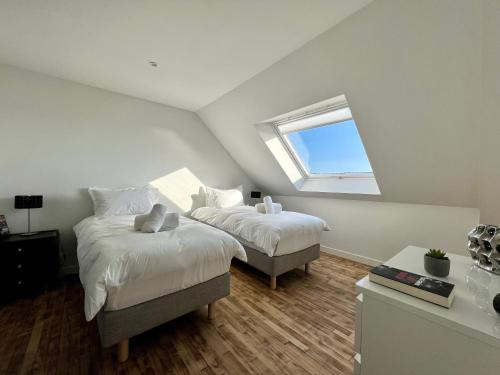 a attic bedroom with two beds and a window at Villa Cotton-vue mer et jacuzzi-6ch in Plobannalec-Lesconil
