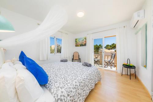 a white bedroom with a bed with blue pillows at Villa Sol in Cala Figuera