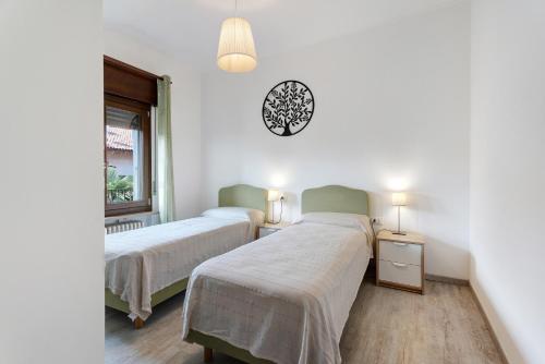 a bedroom with two beds and a clock on the wall at Mansarda Vialba in Germignaga