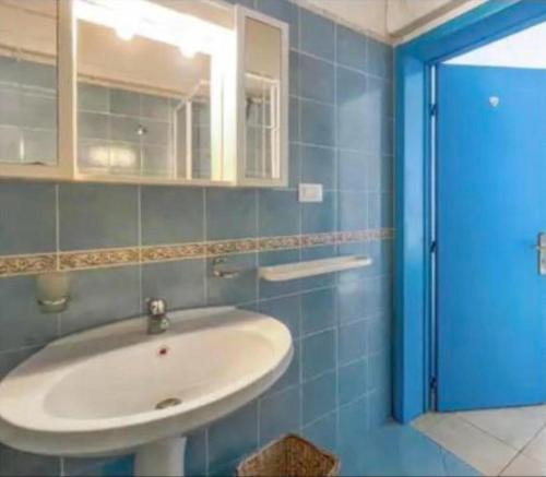 a bathroom with a sink and a blue tiled wall at Mediterranea in Torre Pali