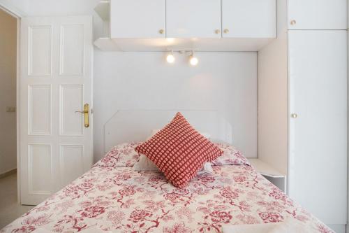 a bedroom with a bed with a red pillow on it at Prealsa Benalmádena in Benalmádena