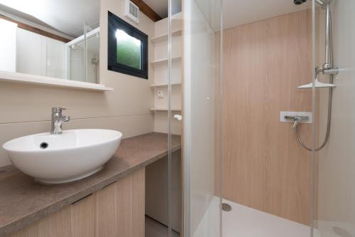 a bathroom with a sink and a glass shower at Chalet 25m2 - Pierres Noires in Plouhinec