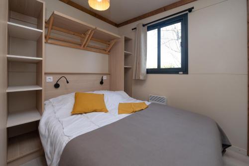 a bedroom with a bed and a window and shelves at Chalet 25m2 - Pierres Noires in Plouhinec