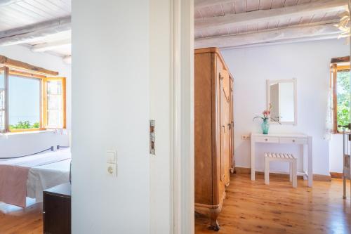 a white room with a bed and a table and window at Villa Iremia Antipaxos in Antipaxos