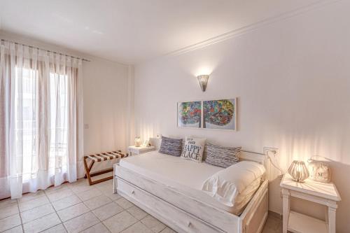 a white bedroom with a bed and a window at Mariners in Alcudia