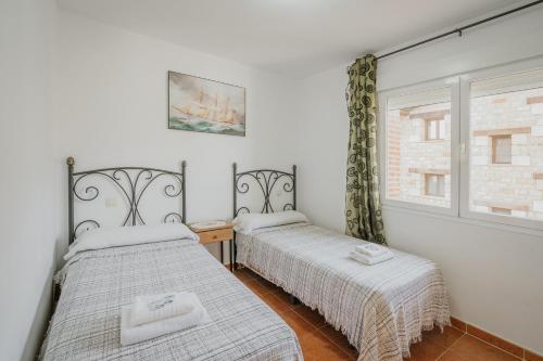 two beds in a room with a window at Los Mirlos in Navaluenga