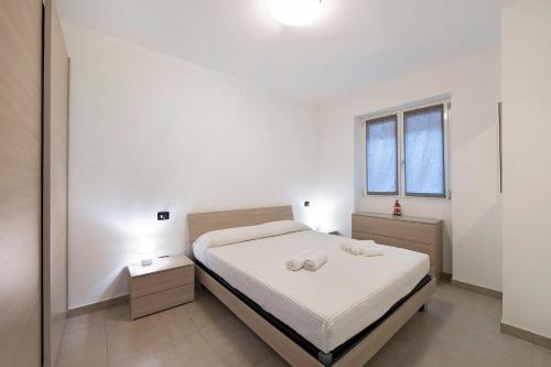a white bedroom with a bed and two windows at Appartamento 2 in Nesso