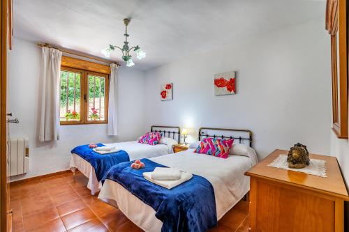 a bedroom with two beds with blue sheets and a table at Ladera de los molinos in Padul