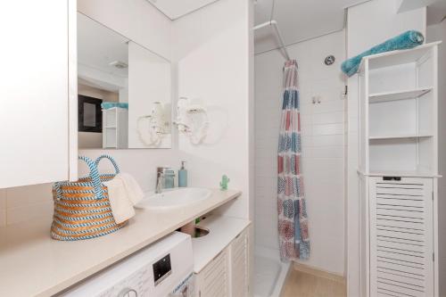 a white bathroom with a sink and a mirror at Sa Perdiu 14 Menorca in Cala Santandria