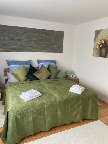 a bedroom with a green bed with two towels on it at Villa Klitzeklein in Bad Belzig