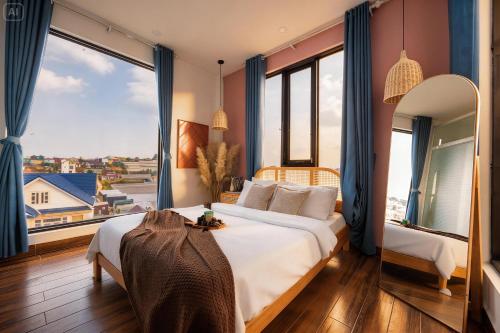 a bedroom with a large bed and large windows at BeYouth Hotel Dalat Valley View in Da Lat