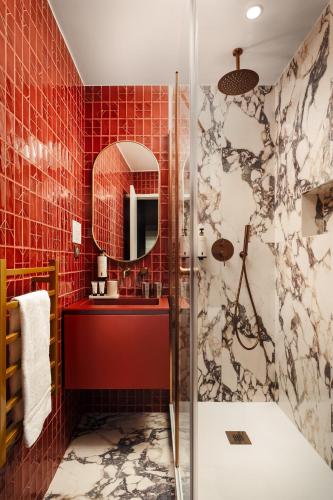 a bathroom with red tiled walls and a shower at Jills Hôtel in Paris