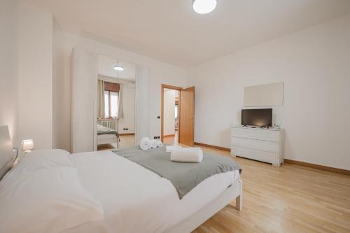 a white bedroom with a large bed and a television at La Fenice Private Gardent Free in Rivoli Veronese