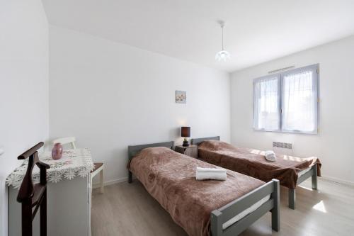 a bedroom with two beds and a table and a window at Le Cœur de Tranche - proche mer in La Tranche-sur-Mer