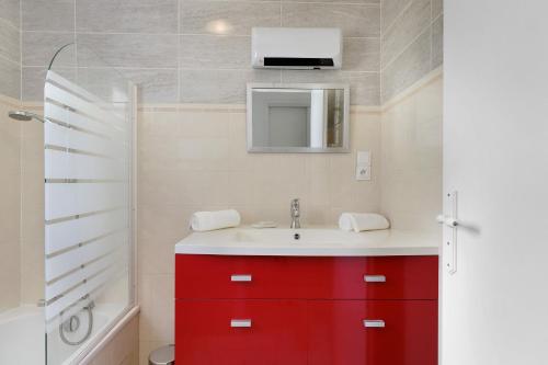 a bathroom with a red cabinet and a sink at Le Cœur de Tranche - proche mer in La Tranche-sur-Mer