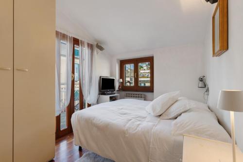 ein weißes Schlafzimmer mit Bett und Fernseher in der Unterkunft Chiavari Elegante in Chiavari