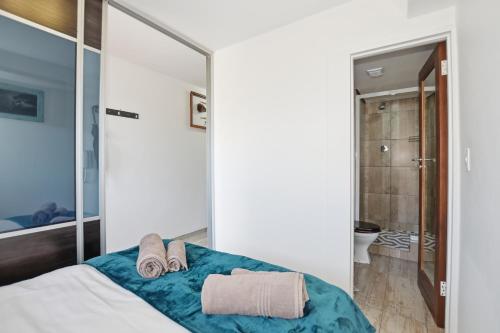 a bedroom with a bed with towels and a mirror at Nautica by the Sea in Cape Town