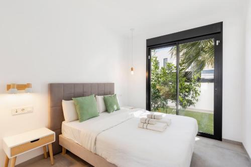 a bedroom with a white bed and a large window at Chalet con Piscina en San Javier in San Javier