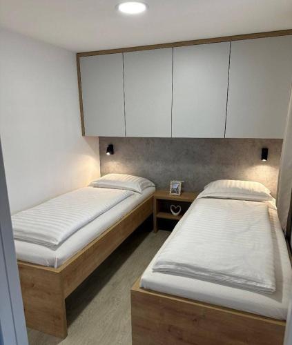 two beds in a room with white cabinets at Mobile Home Ella in Murter