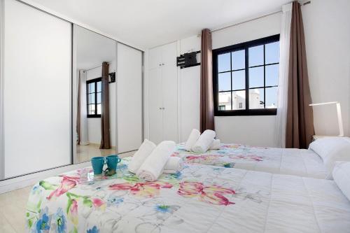 a bedroom with a large bed with a floral bedspread at Casa del Sol Rosa in Corralejo